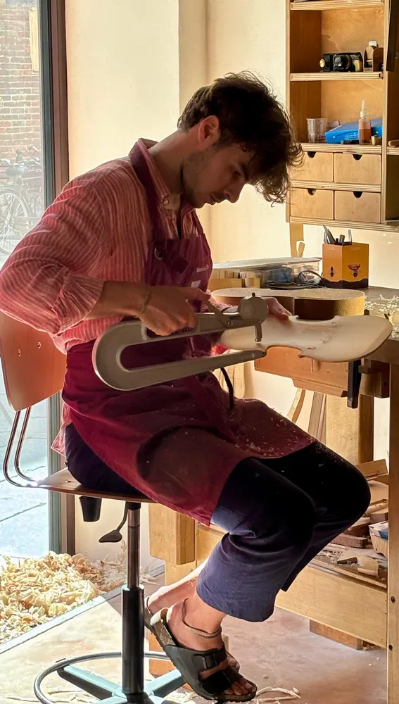 Estudiante luthier afinando medidas en un nuevo violín. Escuela de Cremona Estudiante luthier afinando medidas en un nuevo violín. Escuela de Cremona