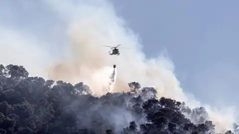 Un helicóptero extinguiendo un incendio forestal Un helicóptero extinguiendo un incendio forestal