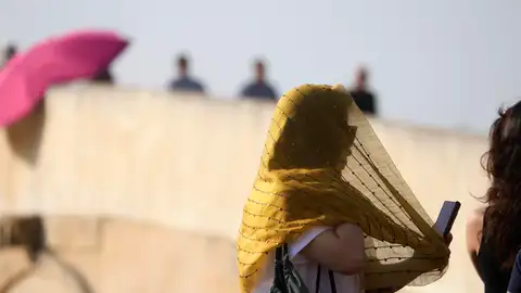 Una turista se cubre la cabeza con un pañuelo mientras camina por el Puente Romano de Córdoba. Una turista se cubre la cabeza con un pañuelo mientras camina por el Puente Romano de Córdoba.