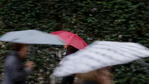 Varias personas se protegen de la lluvia con un paraguas. Varias personas se protegen de la lluvia con un paraguas.