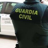 Un agente de la Guardia Civil de espaldas frente a un coche