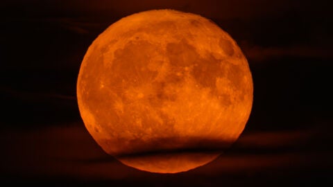  La luna de fresa brilla en el cielo nocturno sobre Brandeburgo, parcialmente oculta por las nubes. 