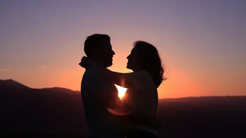 Una pareja haciéndose una foto con un atardecer de fondo Una pareja haciéndose una foto con un atardecer de fondo
