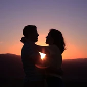 Una pareja haciéndose una foto con un atardecer de fondo Una pareja haciéndose una foto con un atardecer de fondo