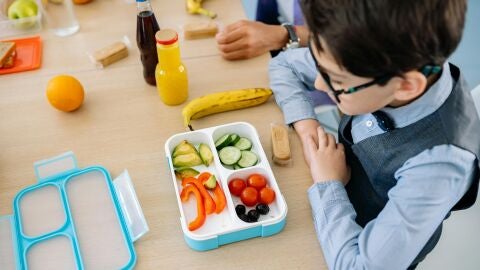 Un ni&ntilde;o frente a una t&aacute;per con frutas y verduras