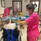 Una sanitaria administra una vacuna a una persona.