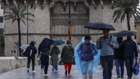 Varias personas con paraguas pasean en Valencia con paraguas por la lluvia Varias personas con paraguas pasean en Valencia con paraguas por la lluvia