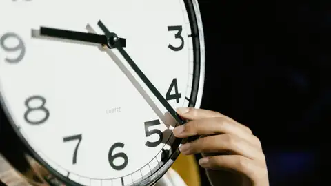Una persona manipulando las agujas de un reloj Una persona manipulando las agujas de un reloj