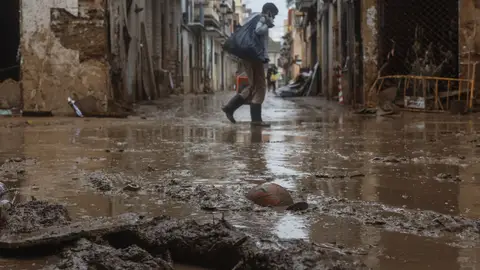 Un hombre pasea por una calle de Paiporta anegada por el barro Un hombre pasea por una calle de Paiporta anegada por el barro