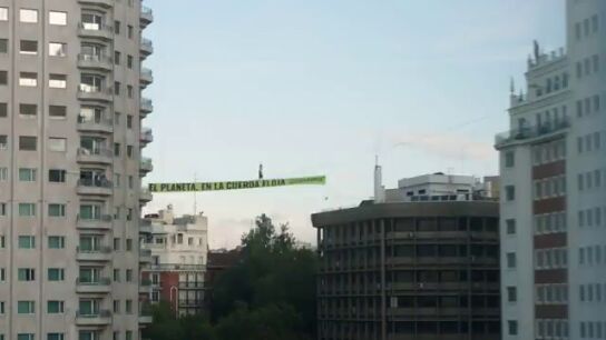 Una activista camina por una cuerda floja a 30 metros de altura en la Plaza de Espa&ntilde;a de Madrid