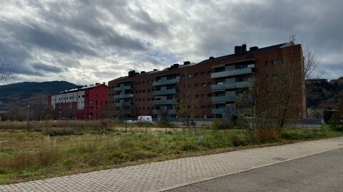 Imatge d'un solar en un poble de muntanya amb edificis de pisos al costat