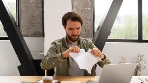 Un trabajador rompe un papel Un trabajador rompe un papel