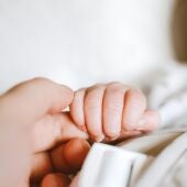 Una madre sostiene la mano de su hijo recién nacido