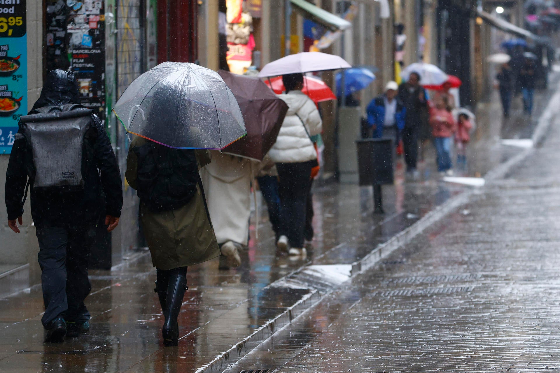 Varias personas se protegen de la lluvia en el centro de Barcelona, este sábado. Varias personas se protegen de la lluvia en el centro de Barcelona, este sábado.