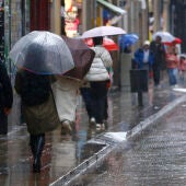 Varias personas se protegen de la lluvia en el centro de Barcelona, este sábado. 