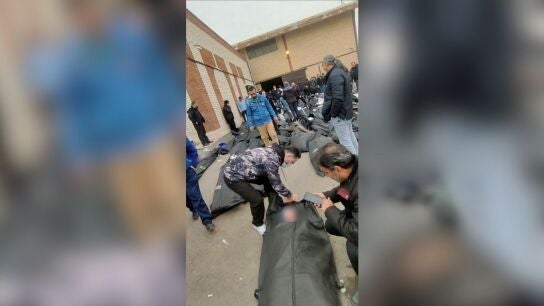 Los cuerpos yacen en bolsas para cad&aacute;veres en el suelo mientras la gente permanece de pie en medio de la escena frente al Centro M&eacute;dico Forense Kahrizak en Teher&aacute;n