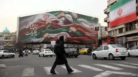Una mujer iraní cruza una calle cerca de una valla publicitaria que dice "Irán es nuestra Patria" en la Plaza Enqelab de Teherán. Una mujer iraní cruza una calle cerca de una valla publicitaria que dice "Irán es nuestra Patria" en la Plaza Enqelab de Teherán.
