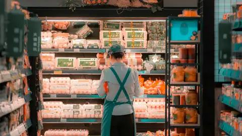 Una trabajadora de un supermercado repone varias cajas de huevos Una trabajadora de un supermercado repone varias cajas de huevos