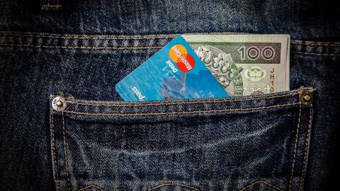 Imatge de la butxaca posterior d'un pantal&oacute; amb una targeta i diners en efectiu