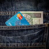 Imatge de la butxaca posterior d'un pantaló amb una targeta i diners en efectiu