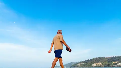 Un hombre pasea por una playa Claves del programa de viajes para mayores de 55 años en Madrid: destinos, requisitos y cómo solicitarlos