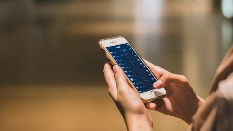 Imagen de archivo de un joven que mira el estado de sus inversiones en su teléfono móvil.