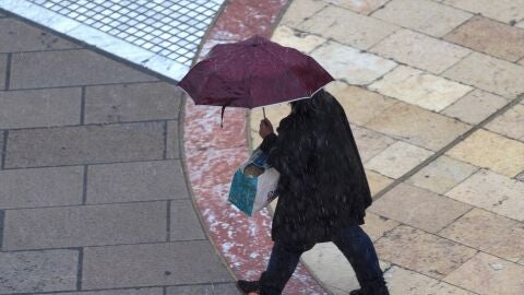 Imagen de archivo de un hombre con un paraguas en una calle.