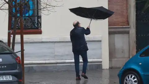 Una persona se protege de la lluvia con su paraguas. - Una persona se protege de la lluvia con su paraguas. -