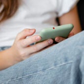 Una adolescente sostiene un teléfono móvil. 