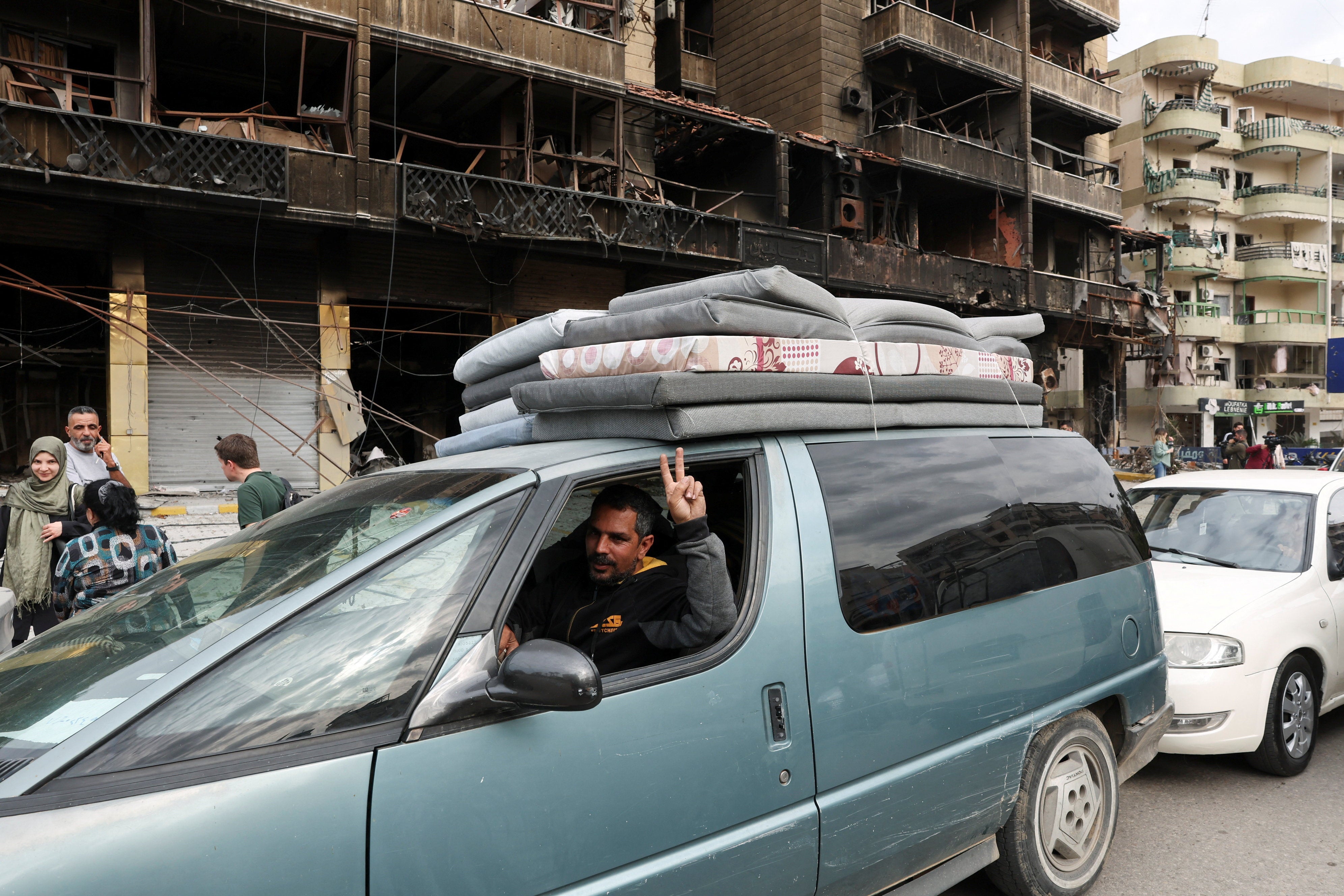 Una persona hace un gesto de victoria desde un vehículo mientras los desplazados se dirigen a sus hogares tras la entrada en vigor de un alto el fuego de 10 días entre Líbano e Israel, en los suburbios del sur de Beirut, Líbano Una persona hace un gesto de victoria desde un vehículo mientras los desplazados se dirigen a sus hogares tras la entrada en vigor de un alto el fuego de 10 días entre Líbano e Israel, en los suburbios del sur de Beirut, Líbano