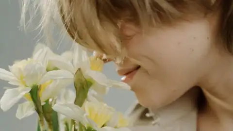 Una mujer oliendo un ramo de flores Una mujer oliendo un ramo de flores