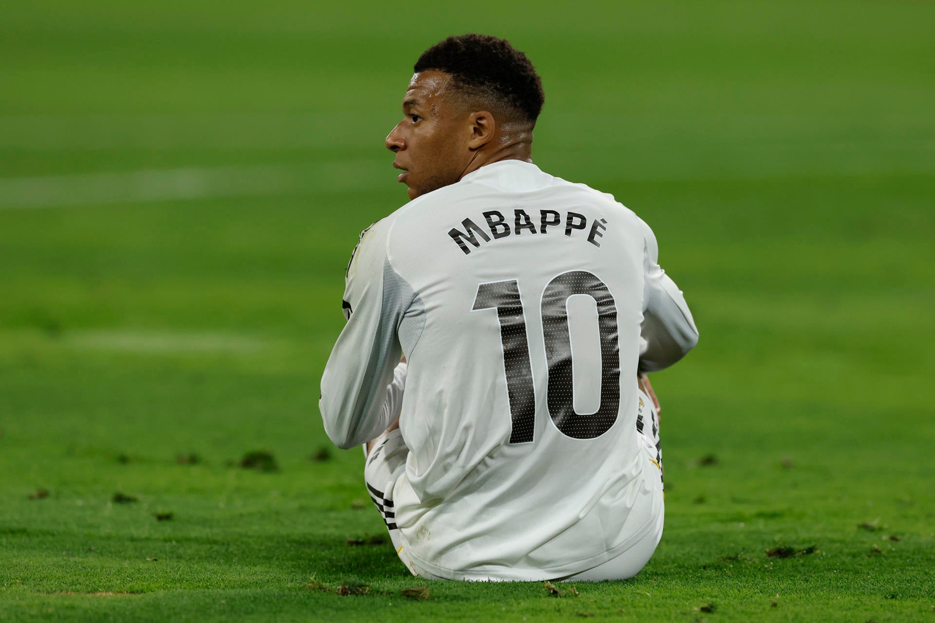 Mbappé sentado en el césped del campo Mbappé sentado en el césped del campo