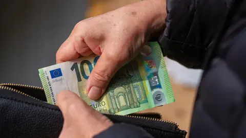 Imagen de archivo de una persona que guarda dinero en su cartera. Imagen de archivo de una persona que guarda dinero en su cartera.