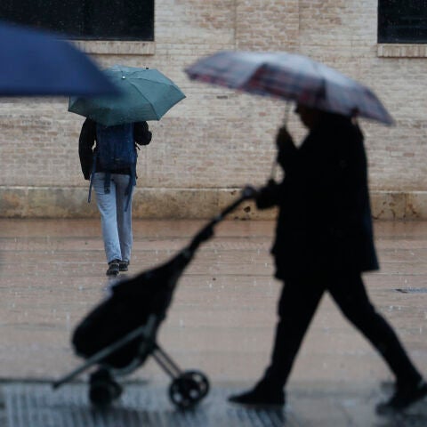 Varias personas con paraguas en un día lluvioso en València.