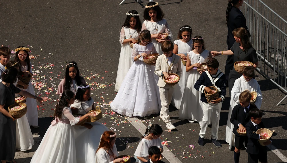 Los niños vestidos de comunión lanzan pétalos de flores durante la procesión Los niños vestidos de comunión lanzan pétalos de flores durante la procesión