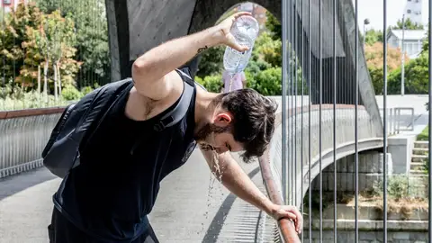Un chico se moja la cabeza para refrescarse del calor Un chico se moja la cabeza para refrescarse del calor