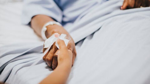 Dos manos agarradas sobre una cama de hospital