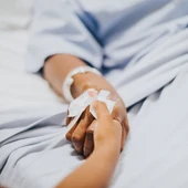 Dos manos agarradas sobre una cama de hospital Dos manos agarradas sobre una cama de hospital