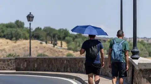 Una persona se protege del calor con un paraguas Una persona se protege del calor con un paraguas