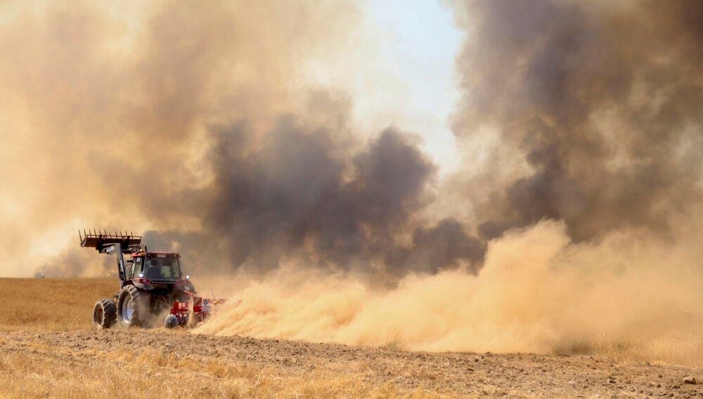 Un tractor intenta frenar el avance del fuego