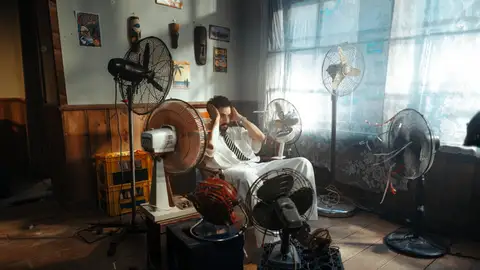 Imagen de archivo de un hombre con varios ventiladores intentando sobrellevar una ola de calor Imagen de archivo de un hombre con varios ventiladores intentando sobrellevar una ola de calor
