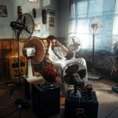 Imagen de archivo de un hombre con varios ventiladores intentando sobrellevar una ola de calor