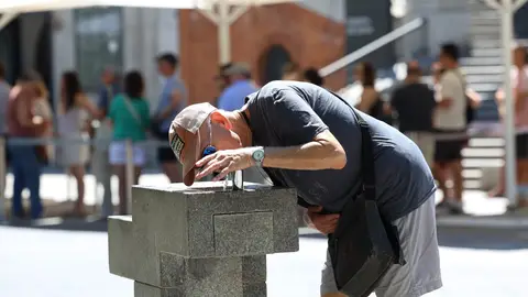 Un hombre bebe agua de una fuente durante la ola de calor en España. Un hombre bebe agua de una fuente durante la ola de calor en España.