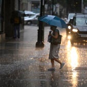 Una mujer cruza una calle de la ciudad de Castellón bajo una intensa lluvia.. 