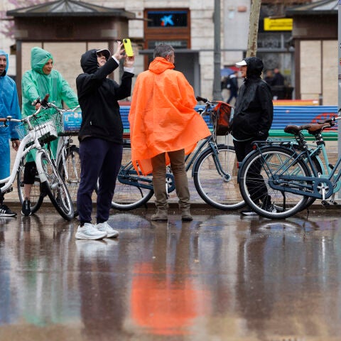 Varias personas se protegen de la lluvia con chubasqueros en València en un día de lluvia. 