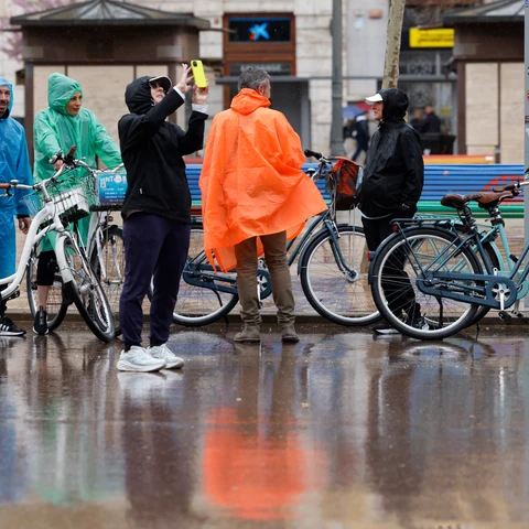 Varias personas se protegen de la lluvia con chubasqueros en València en un día de lluvia.