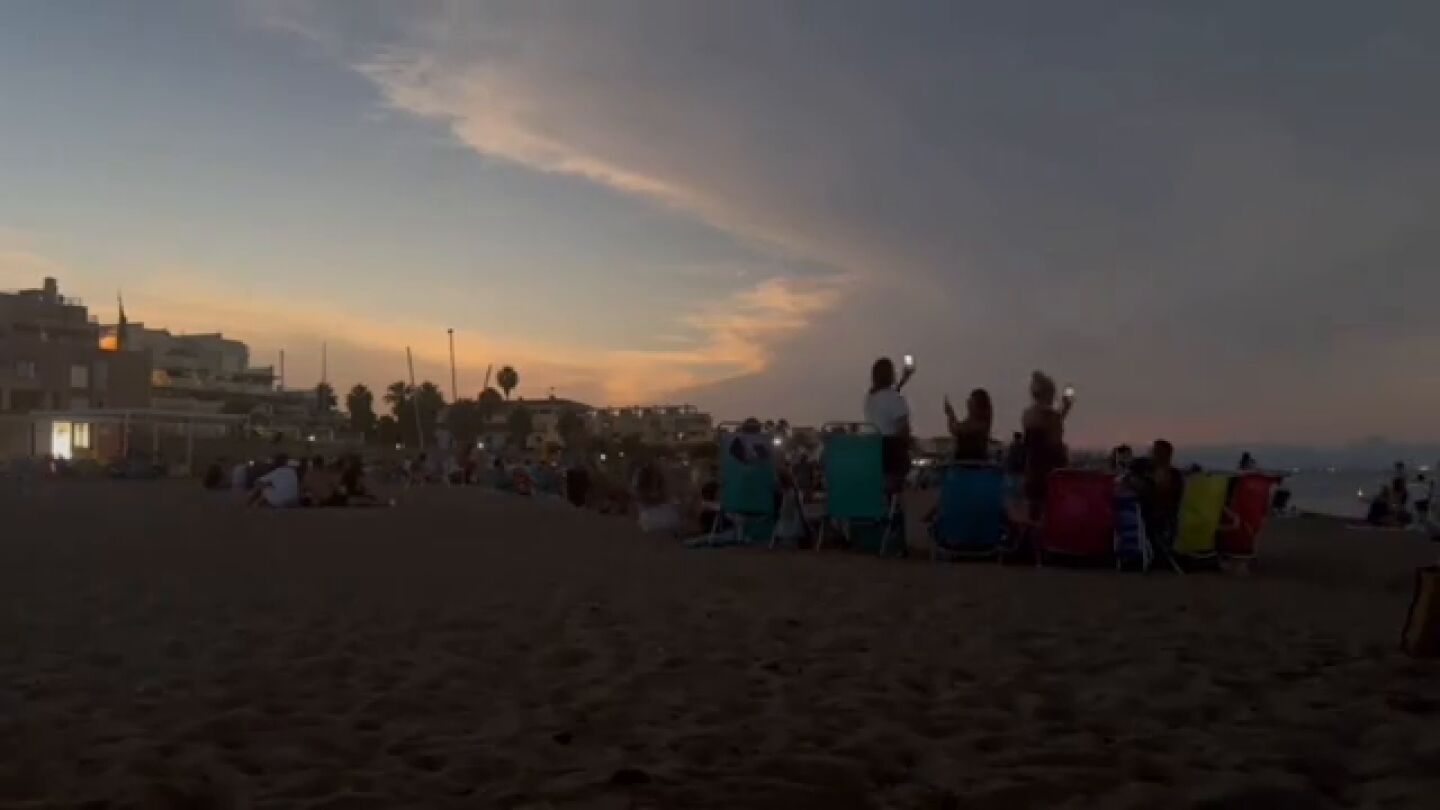 Personas viendo el eclipse en la playa de Denía 