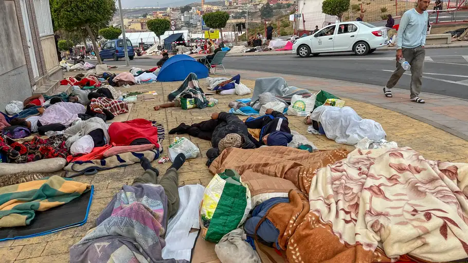 Migrantes duermen en la calle este domingo a la espera de acceder al campamento temporal de la explanada de embolsamiento de Loma Colmenar de Ceuta, que continúa sin capacidad suficiente para reubicar más migrantes. Migrantes duermen en la calle este domingo a la espera de acceder al campamento temporal de la explanada de embolsamiento de Loma Colmenar de Ceuta, que continúa sin capacidad suficiente para reubicar más migrantes.
