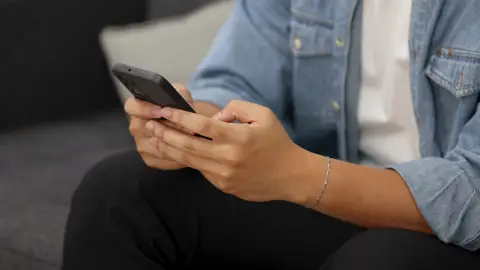 Una persona con un teléfono móvil Una persona con un teléfono móvil