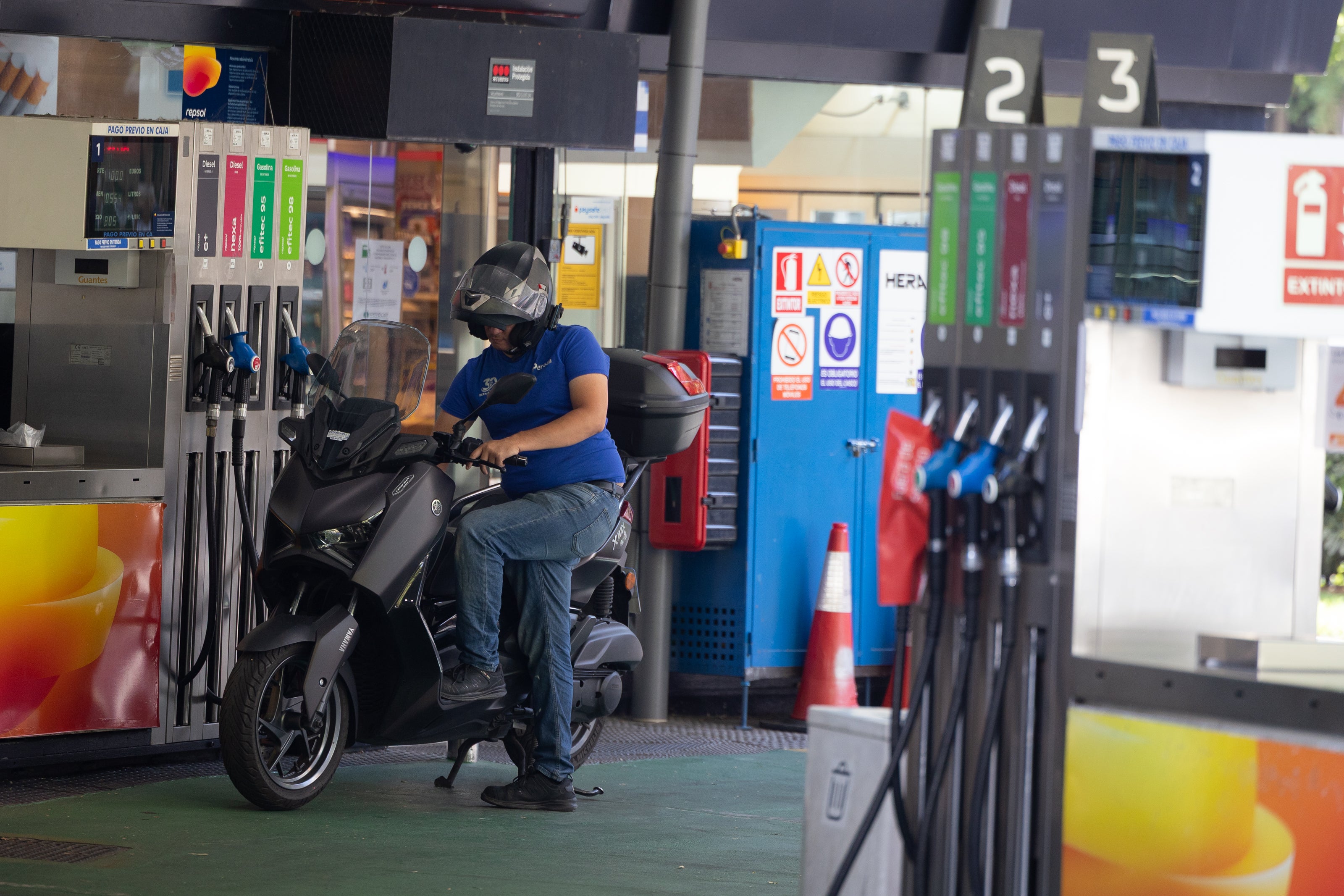 Una motocicleta parando en una gasolinera Una motocicleta parando en una gasolinera